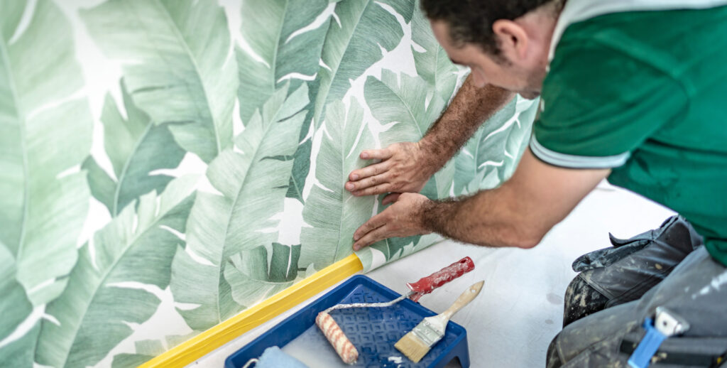 fleißiger Handwerker bringt eine Mustertapete an die Wand an